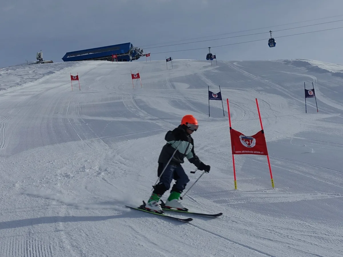 Ein Kind fährt auf einer Skipiste ein Rennen.